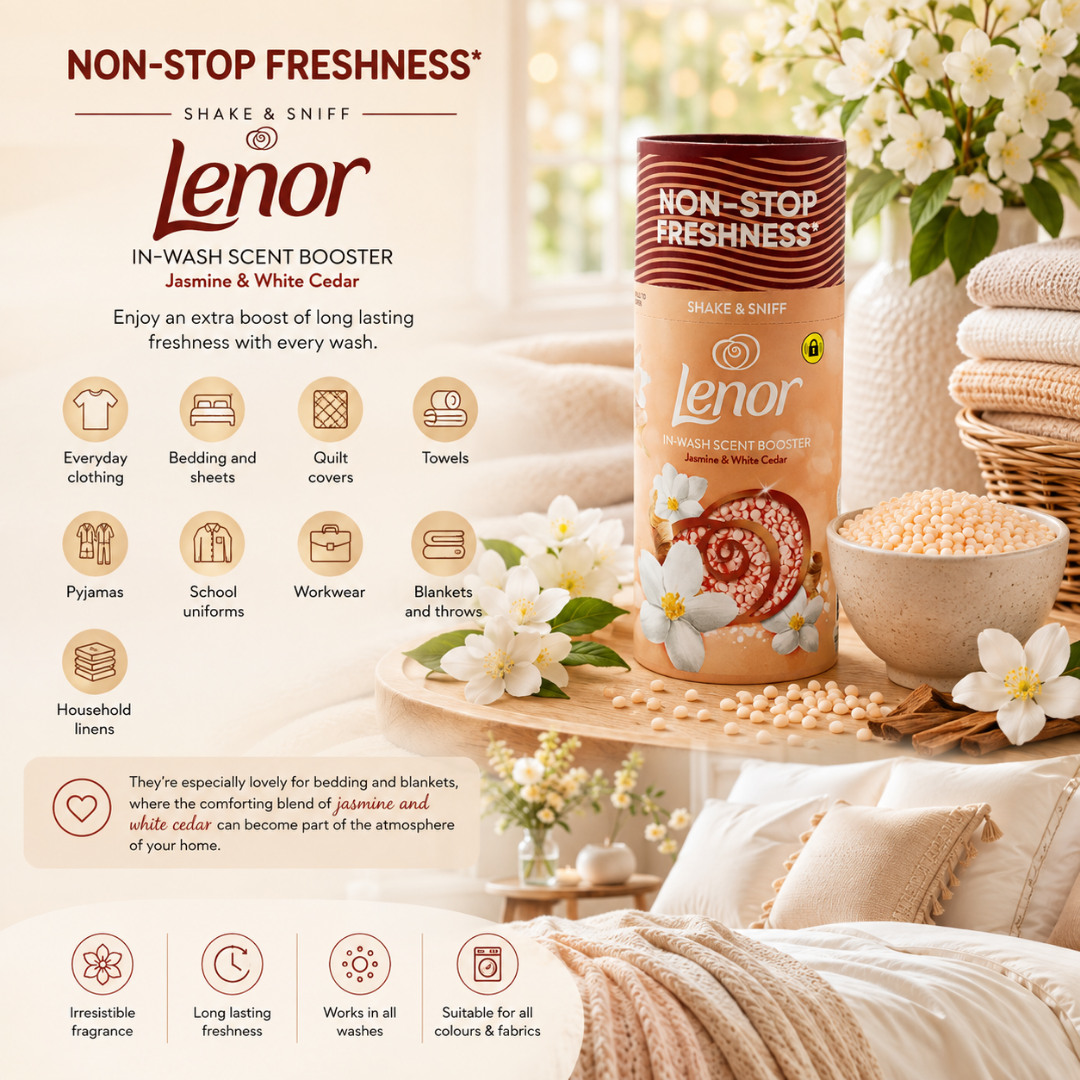 Lenor Non-Stop Freshness Jasmine & White Cedar scent booster in a cylindrical container, displayed on a wooden tray with a bowl of seeds and white flowers, surrounded by cozy home textiles and bedding.